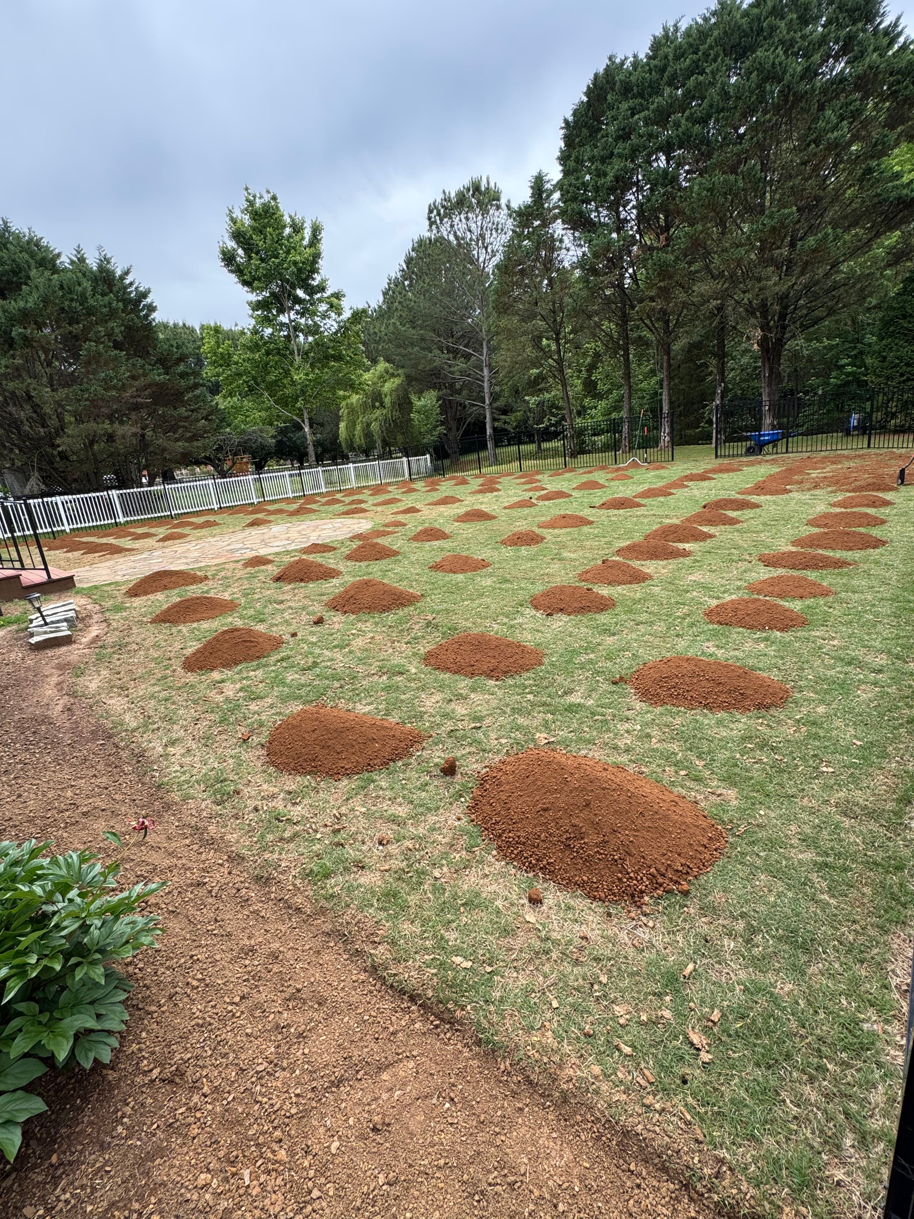 Piles of leveling sand staged across a backyard before spreading in Huntsville, AL